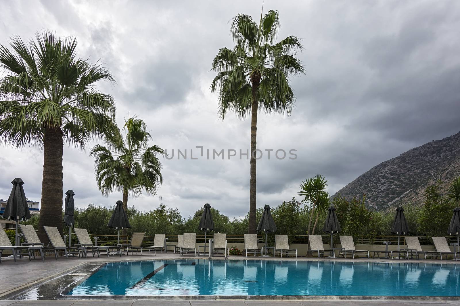 Outdoor swimming pool with sunbeds and umbrellas in cloudy weather
