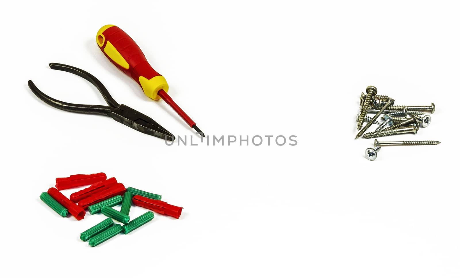 Screwdriver, pliers, screws and plastic dowels on a white background