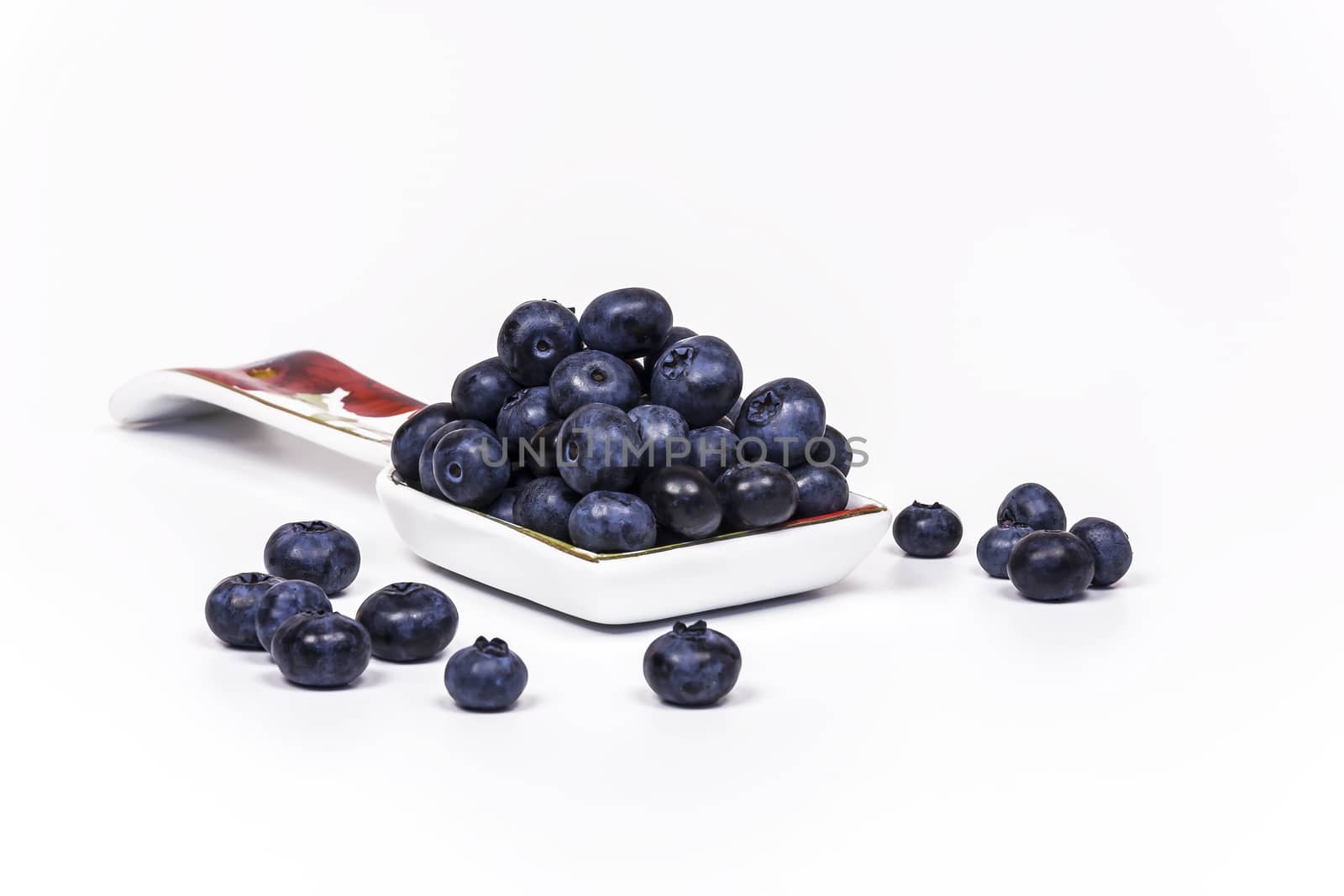 Spoon with large blueberry berries lie on a light background