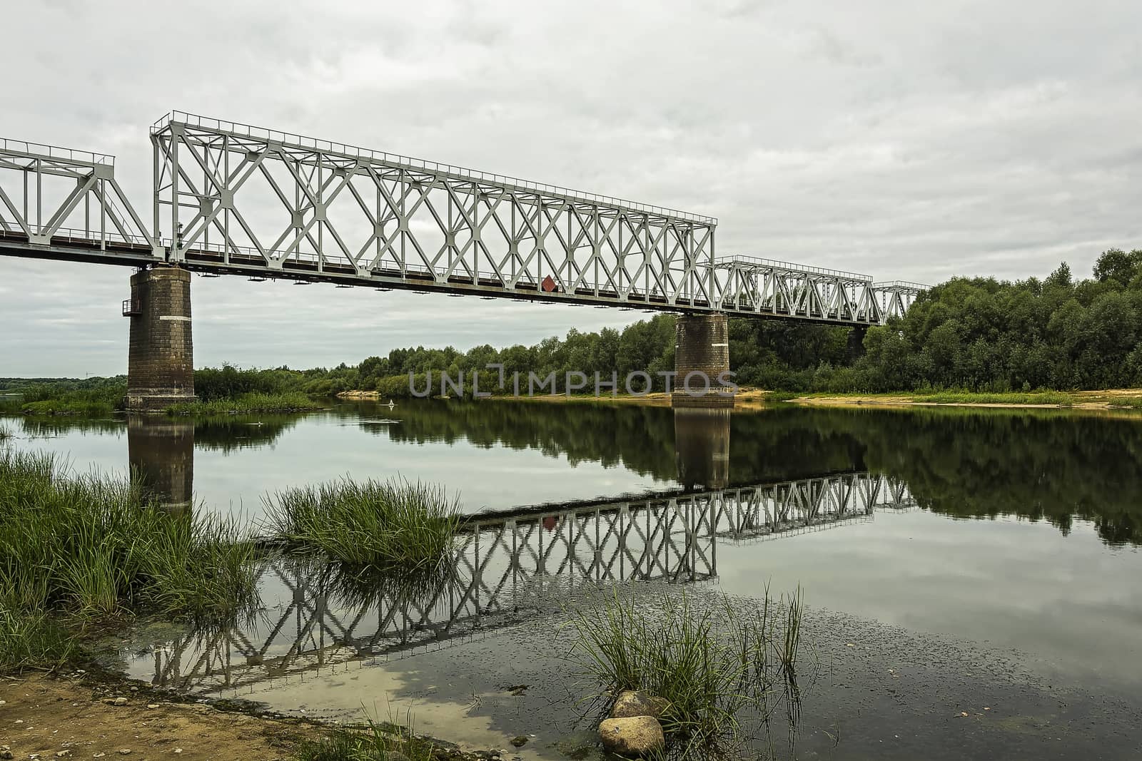 Over the river bed on the concrete supports there is a railway bridge