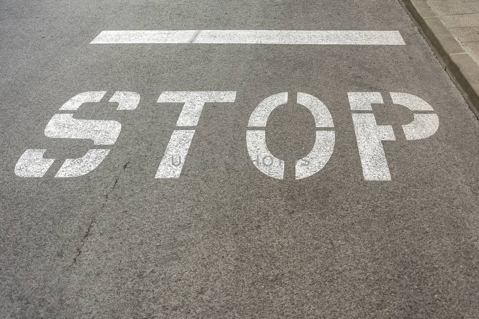 On the roadway of the road there is a sign "STOP"