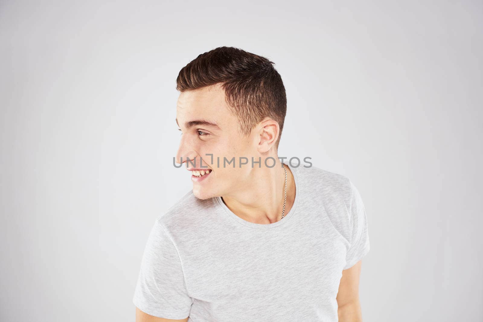 Man in a white t-shirt emotions gestures with hands close-up cropped view light background. High quality photo