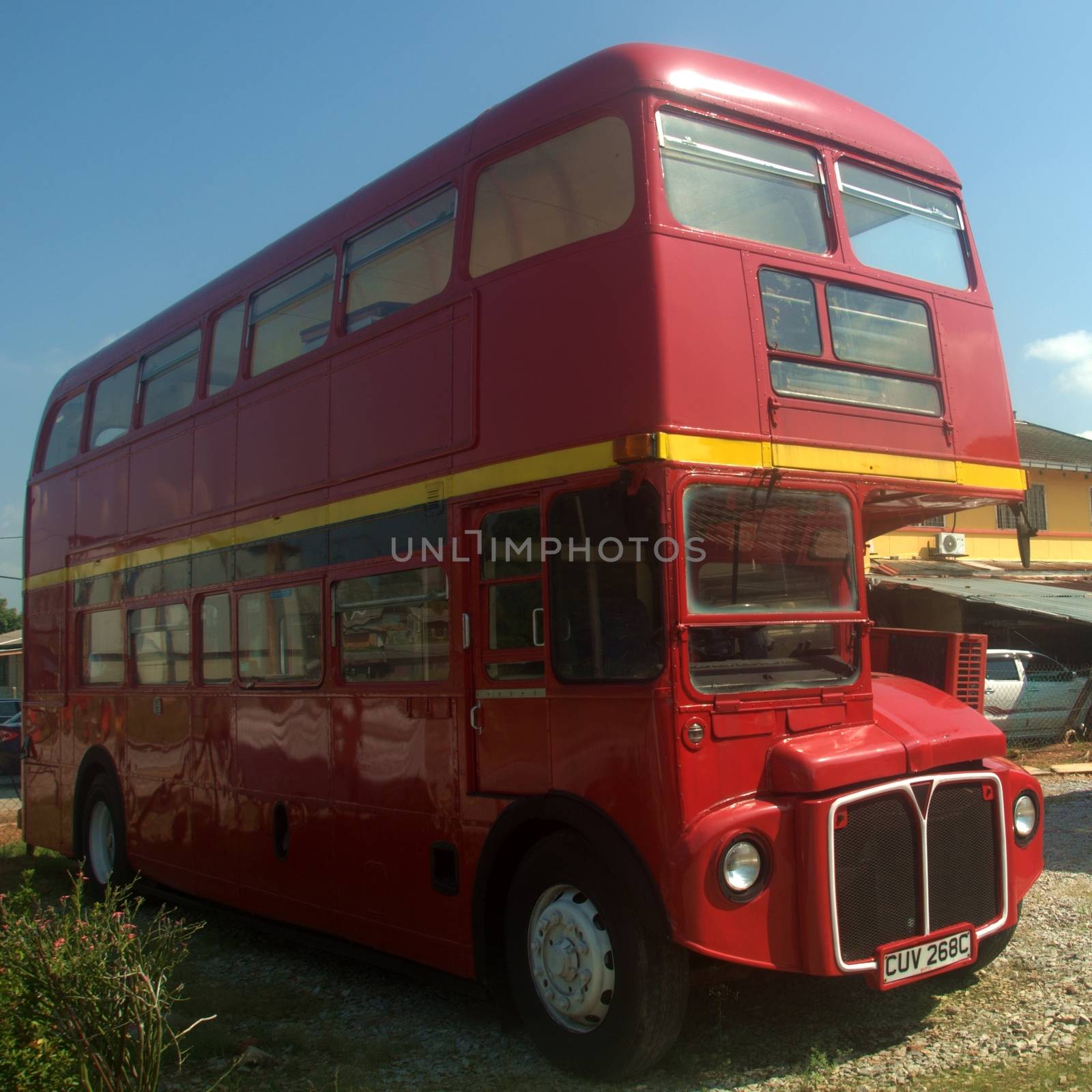 an old model double decker red bus parked in front of a house in Port Dickson Malaysia