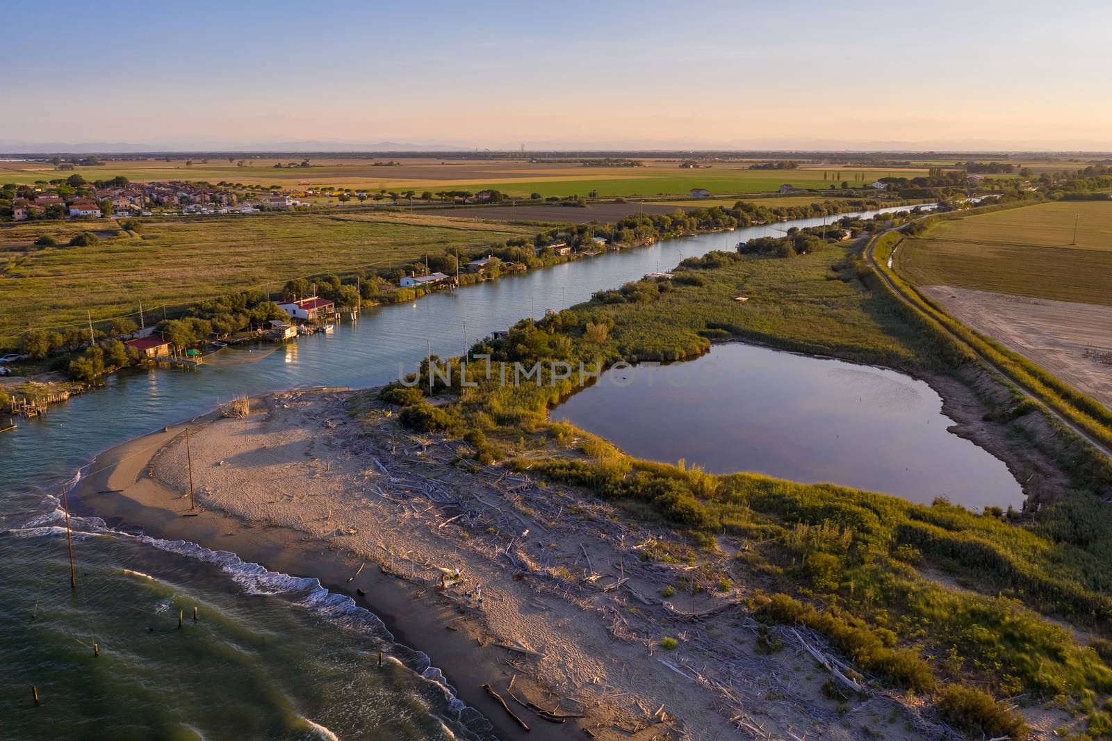 beautiful landscapes of the valleys near Ravenna ,Fiumi Uniti, where the river flows into the sea with the typical fishermen's huts at sunset