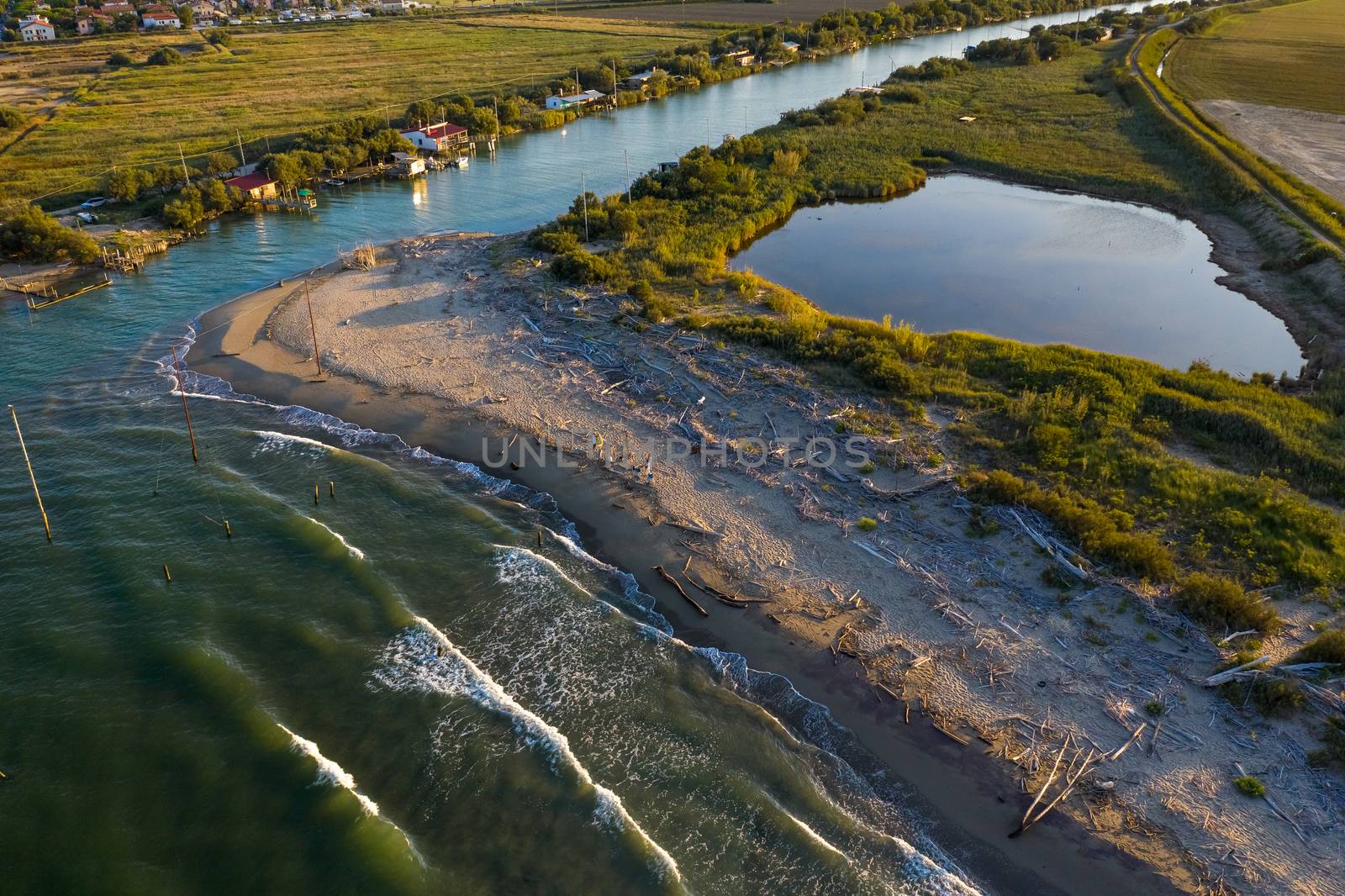 beautiful landscapes of the valleys near Ravenna ,Fiumi Uniti, where the river flows into the sea with the typical fishermen's huts at sunset