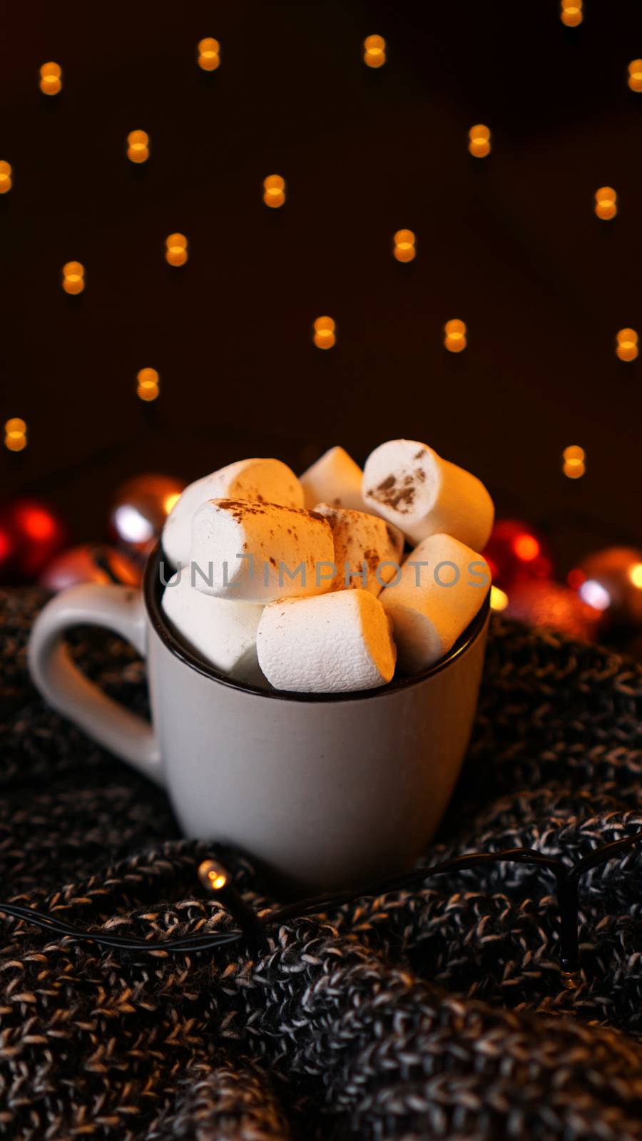 Christmas hot chocolate with marshmallows with lights bokeh. Selective focus - vertical photo