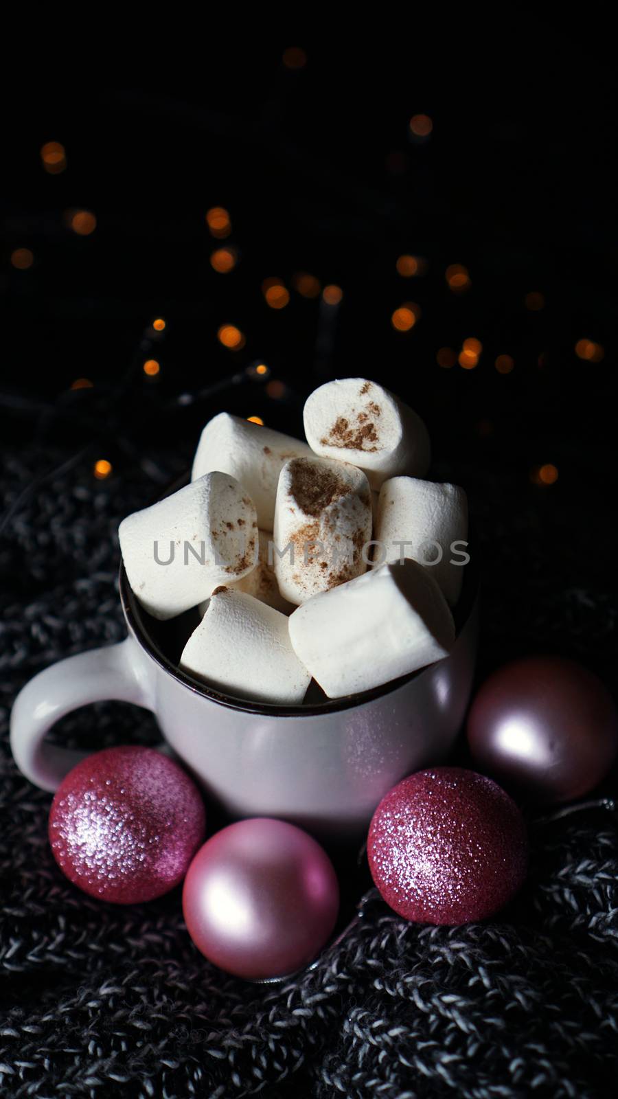 Christmas hot chocolate with marshmallows on a table with lights bokeh. Selective focus - vertical photo