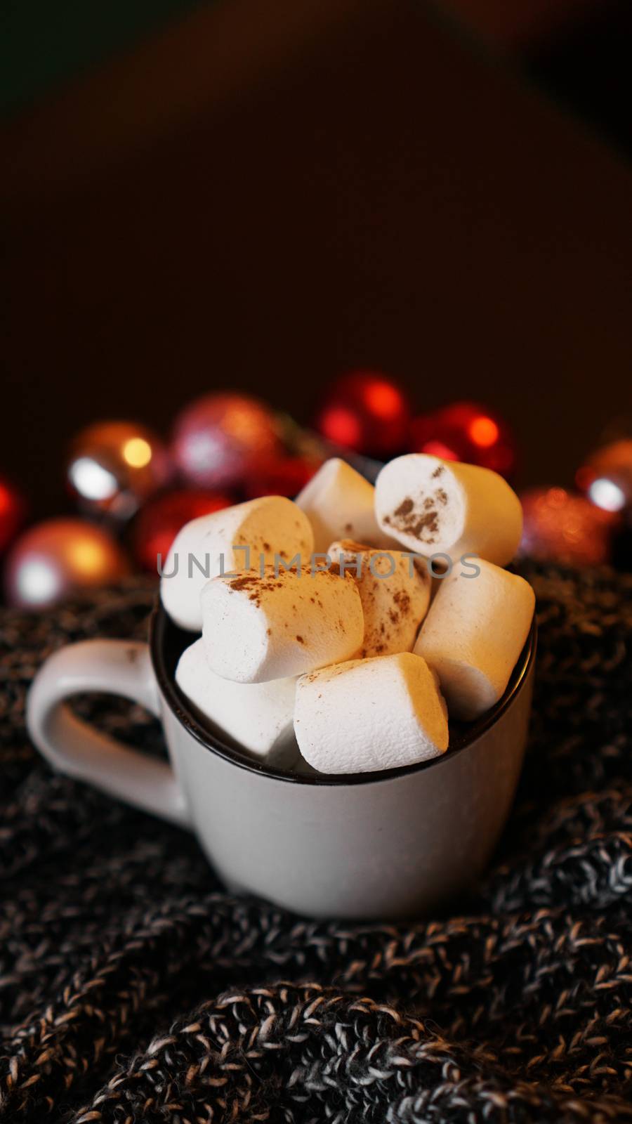 Christmas hot chocolate with marshmallows with lights bokeh. Selective focus - vertical photo