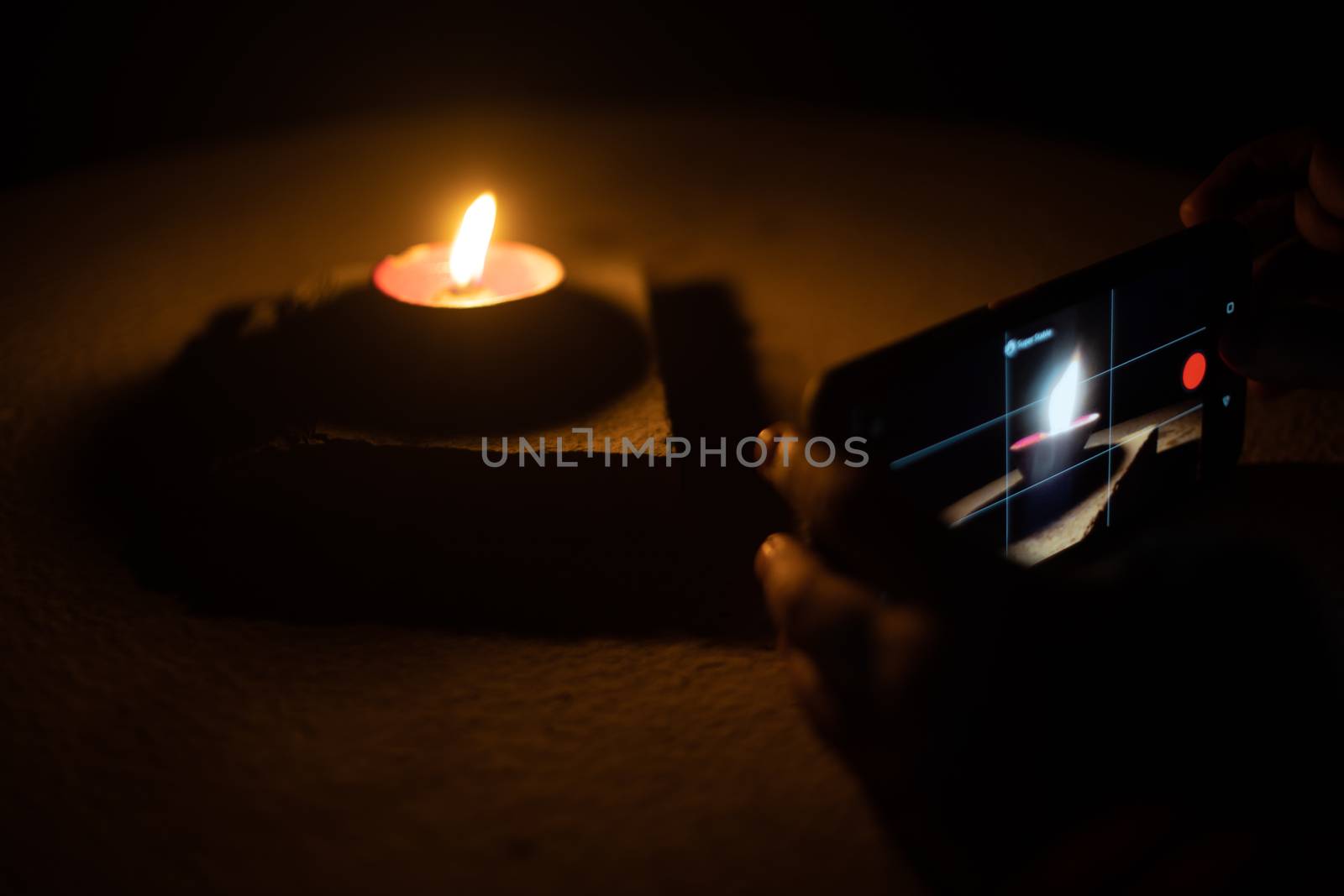 Man woman taking low light pictures of a diya oil lamp with a mobile phone for sharing images on the hindu festival of diwali. Shows the immense influence of social media and technology like low light capable cameras on traditional festivals like the hindu festival