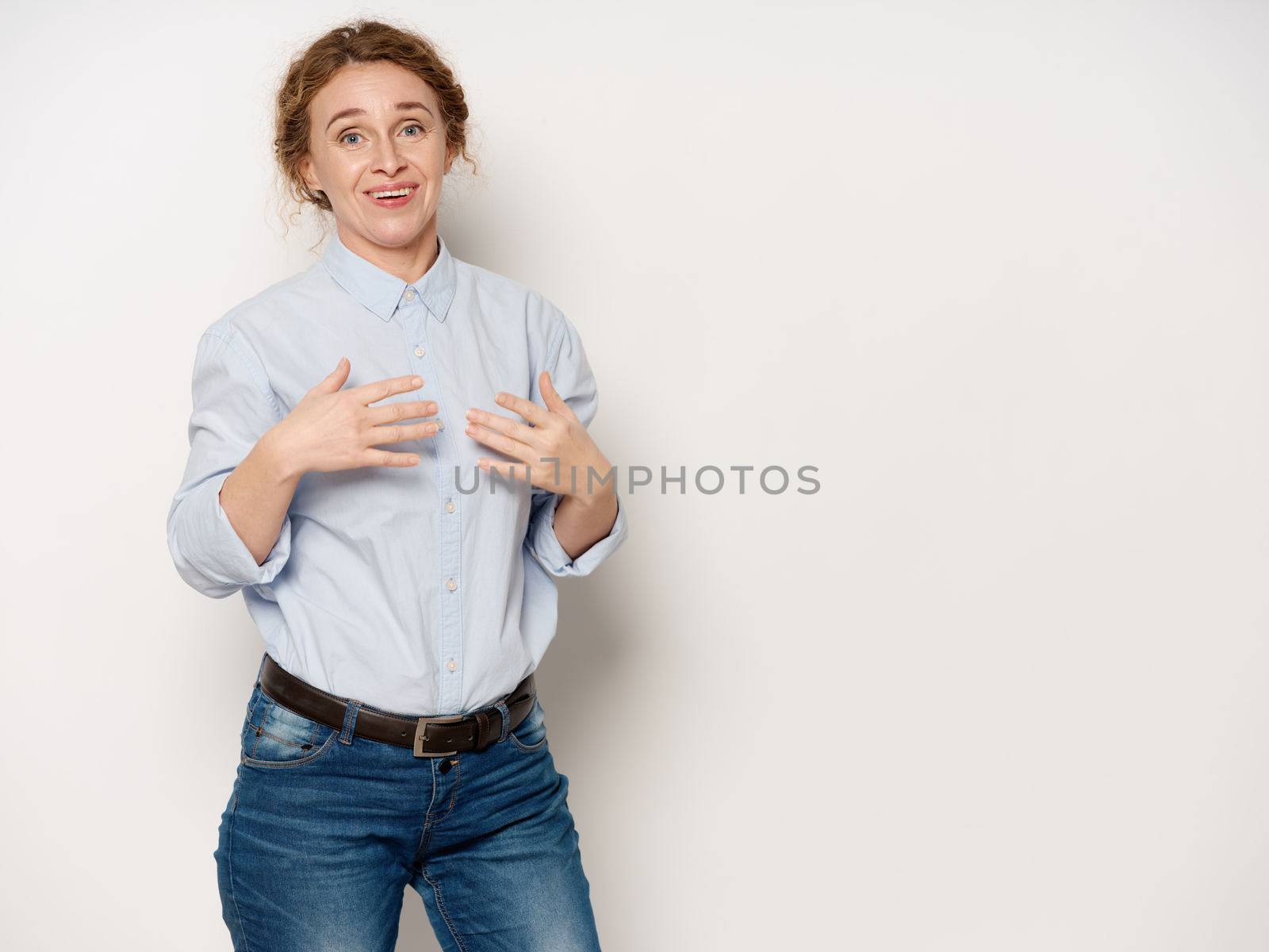 An elderly woman in a shirt shows her hands to herself on an isolated background