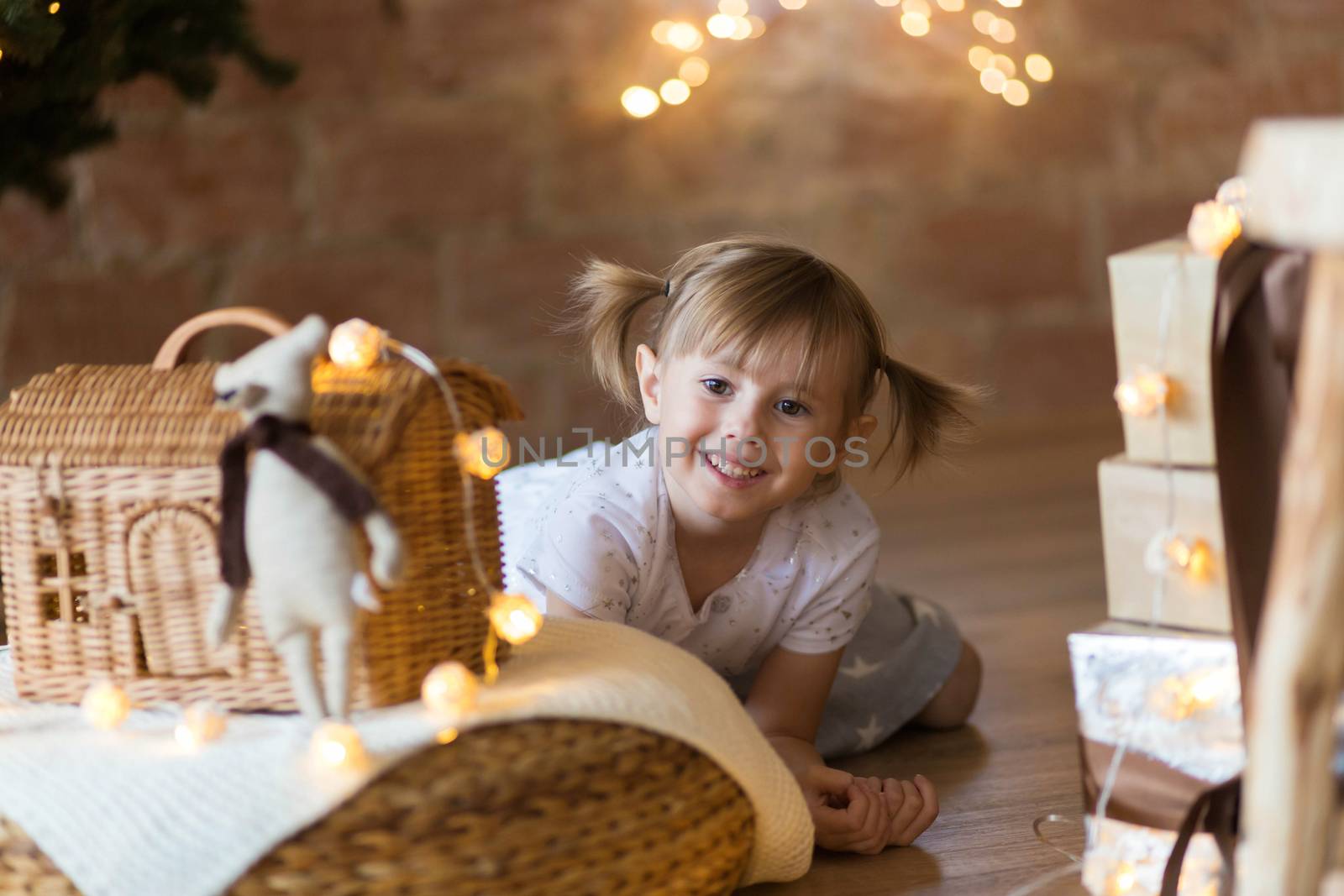 .Adorable little girl sitting on the floor among the new year garlands.