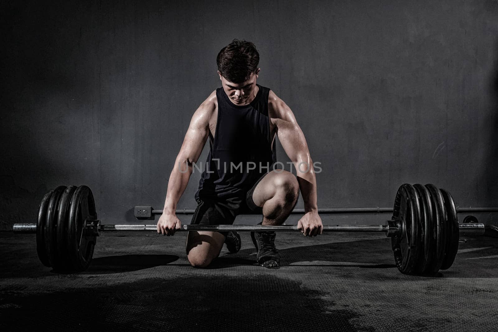 Strong fitness man doing arm workout with barbells in the gym