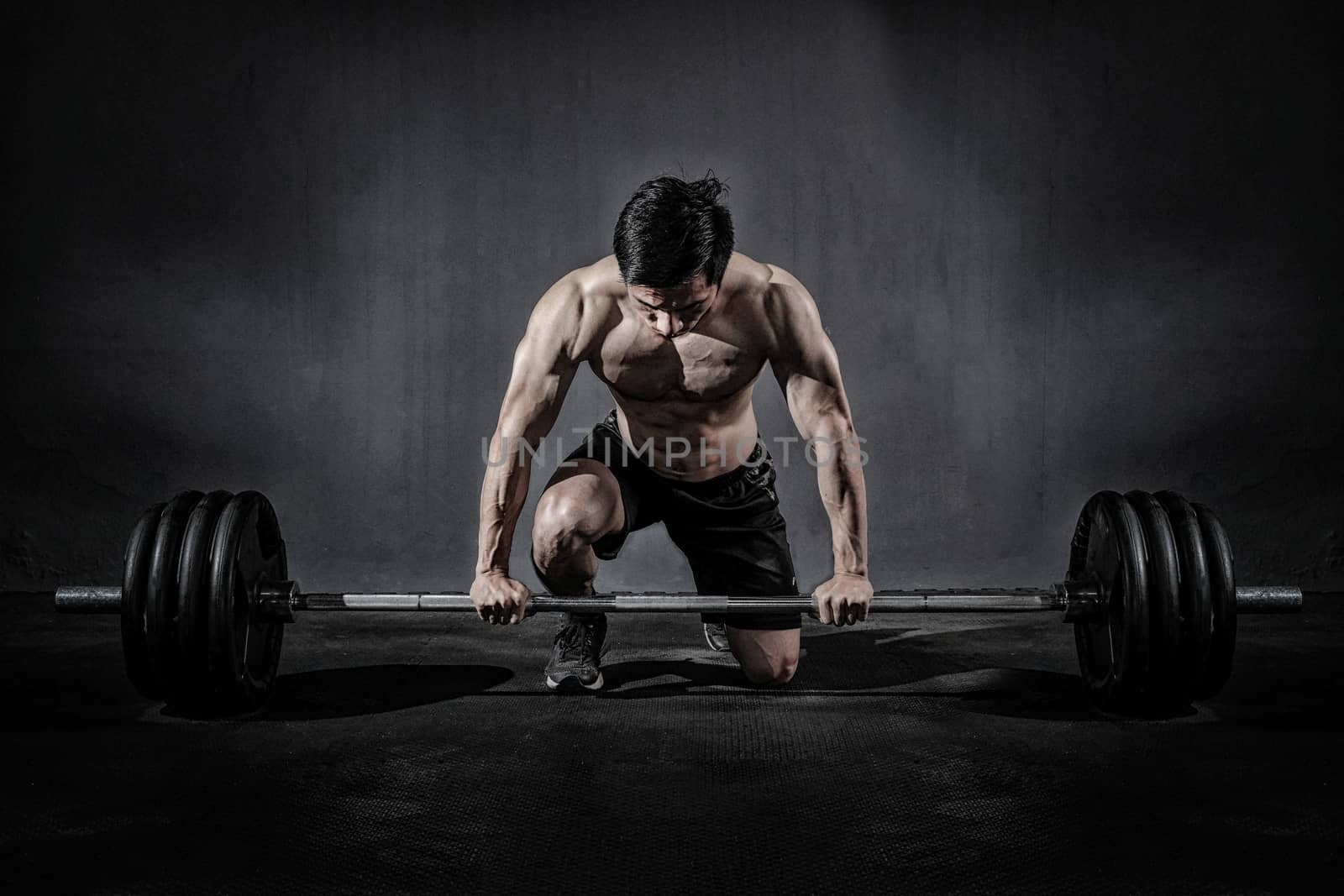 Strong fitness man doing arm workout with barbells in the gym