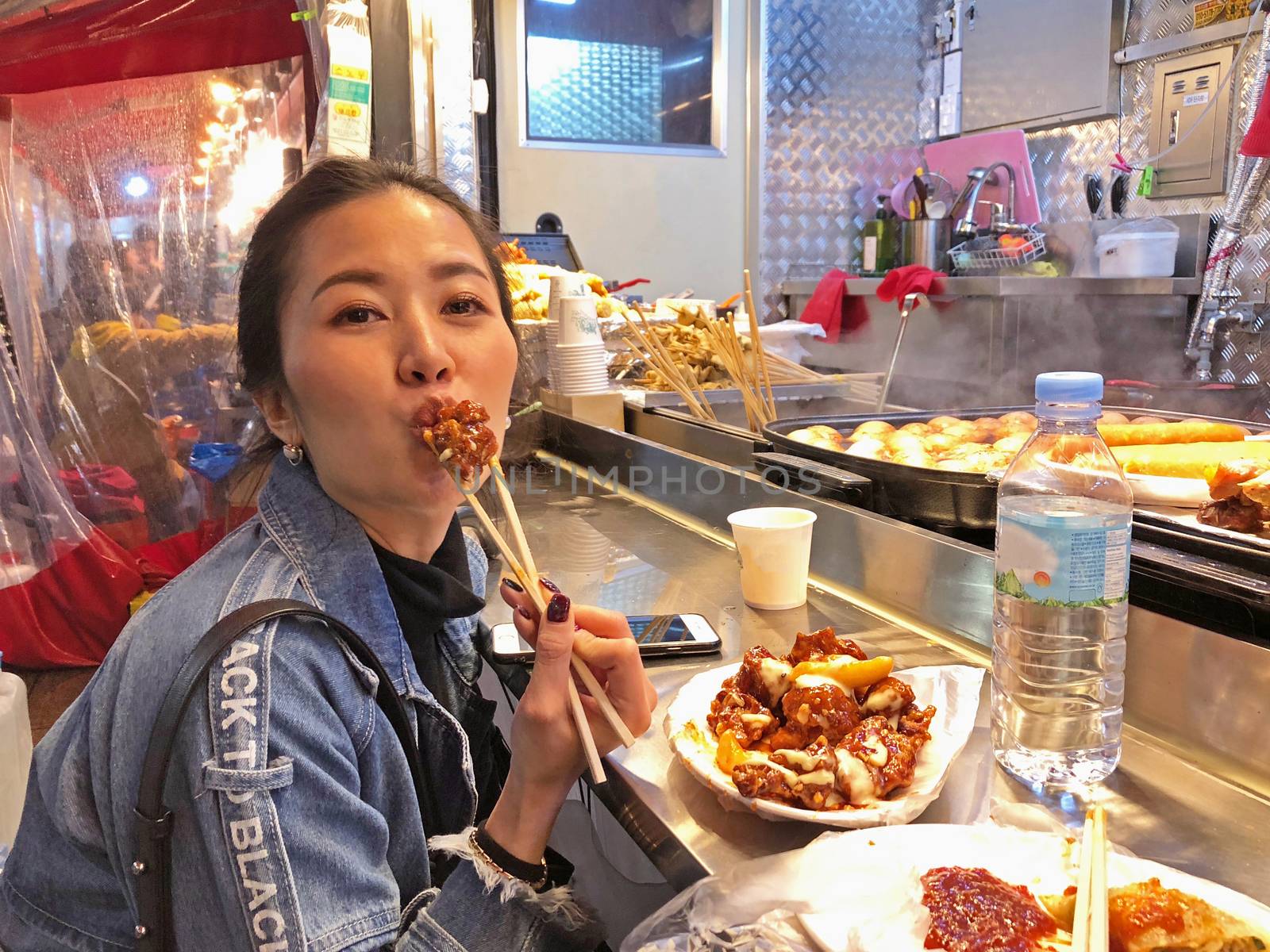 Young woman eating crunchy korean fried chicken street food in Seoul, South Korea