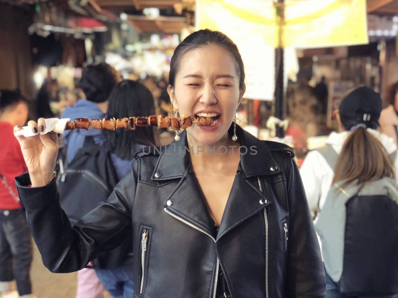 Young woman eating Steamed Octopus Legs at  at Myeong-dong stree by Surasak