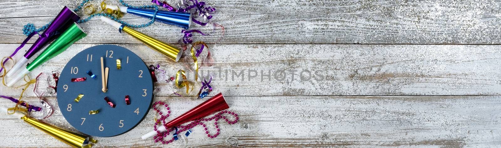 Happy New Year concept with clock approaching midnight on white rustic wooden background plus party decorations 