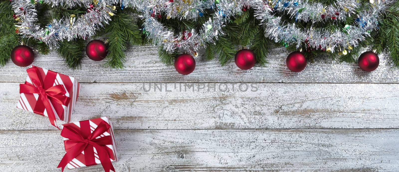 Border of Evergreen branches with tinsel decoration and gift boxes for Christmas or New Year holiday background 