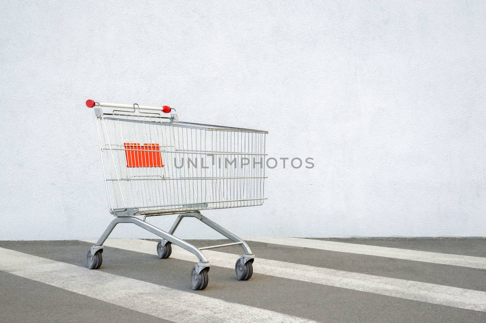 Empty Grocery Cart on the White Wall Store. Trolley at the Supermarket Background. E-commerce. Shopping Concept. Side View. Shopping Cart Trolley Stands near Mall with Copy Space. Black Friday Sale by synel