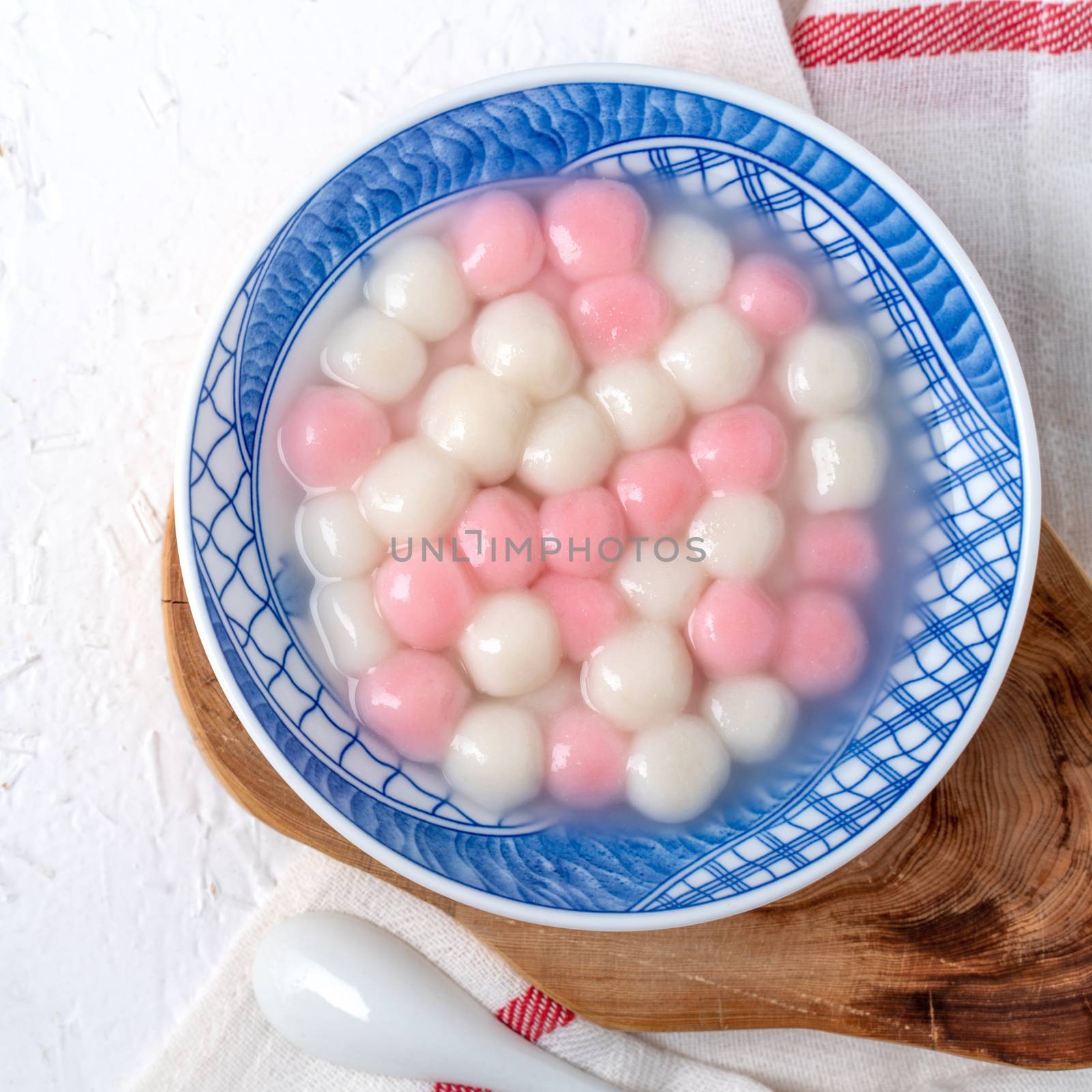 Top view of red and white tangyuan in blue bowl on white backgro by ROMIXIMAGE