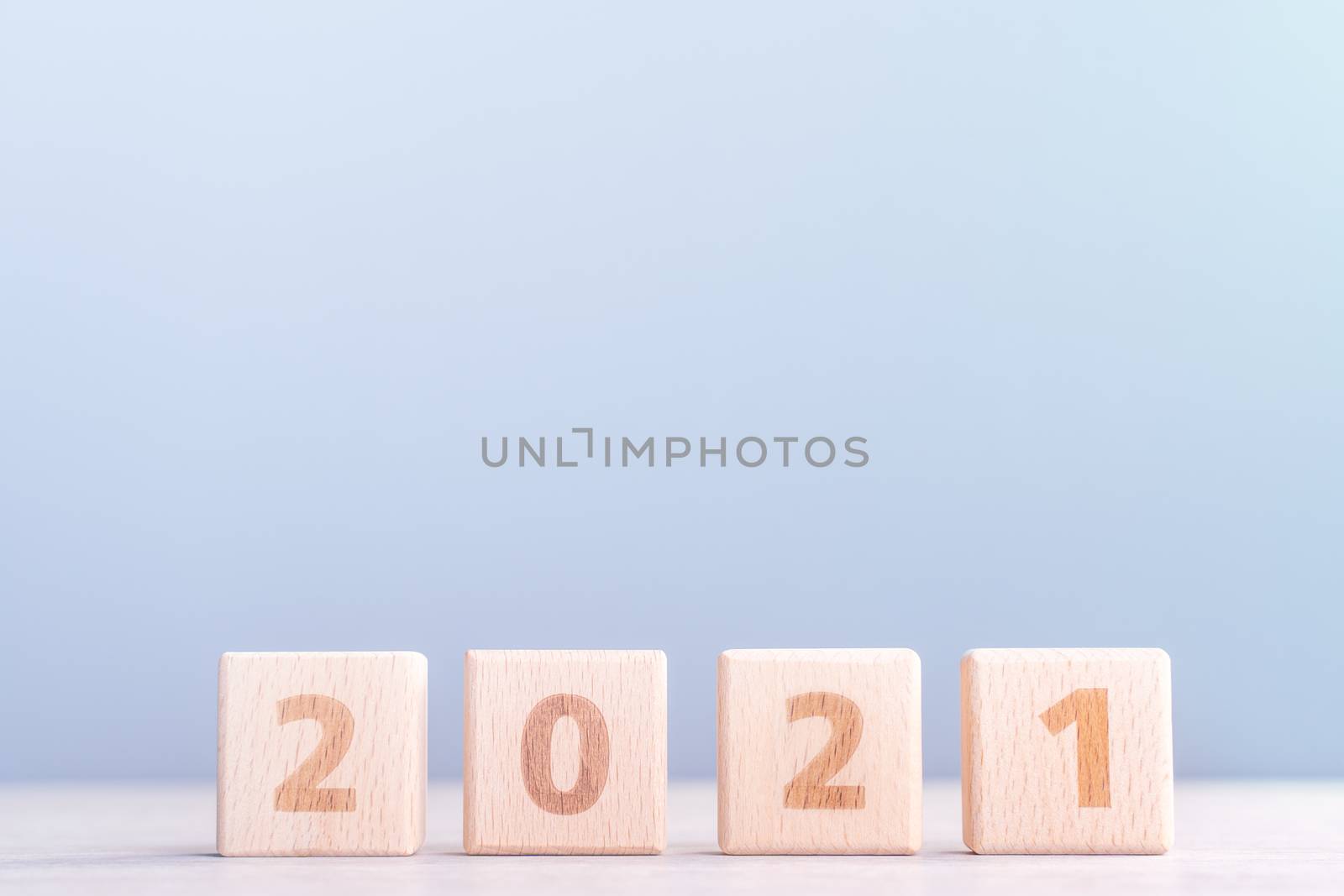 2021 New Year abstract design concept - Number wood block cubes isolated on wooden table and light mist blue background.