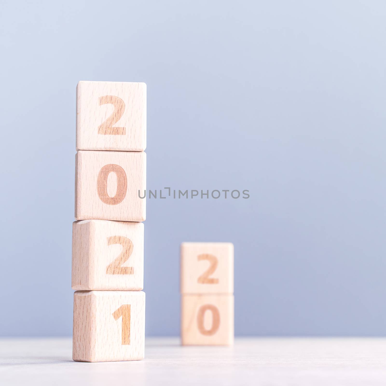 2021 New Year abstract design concept - Number wood block cubes isolated on wooden table and light mist blue background.