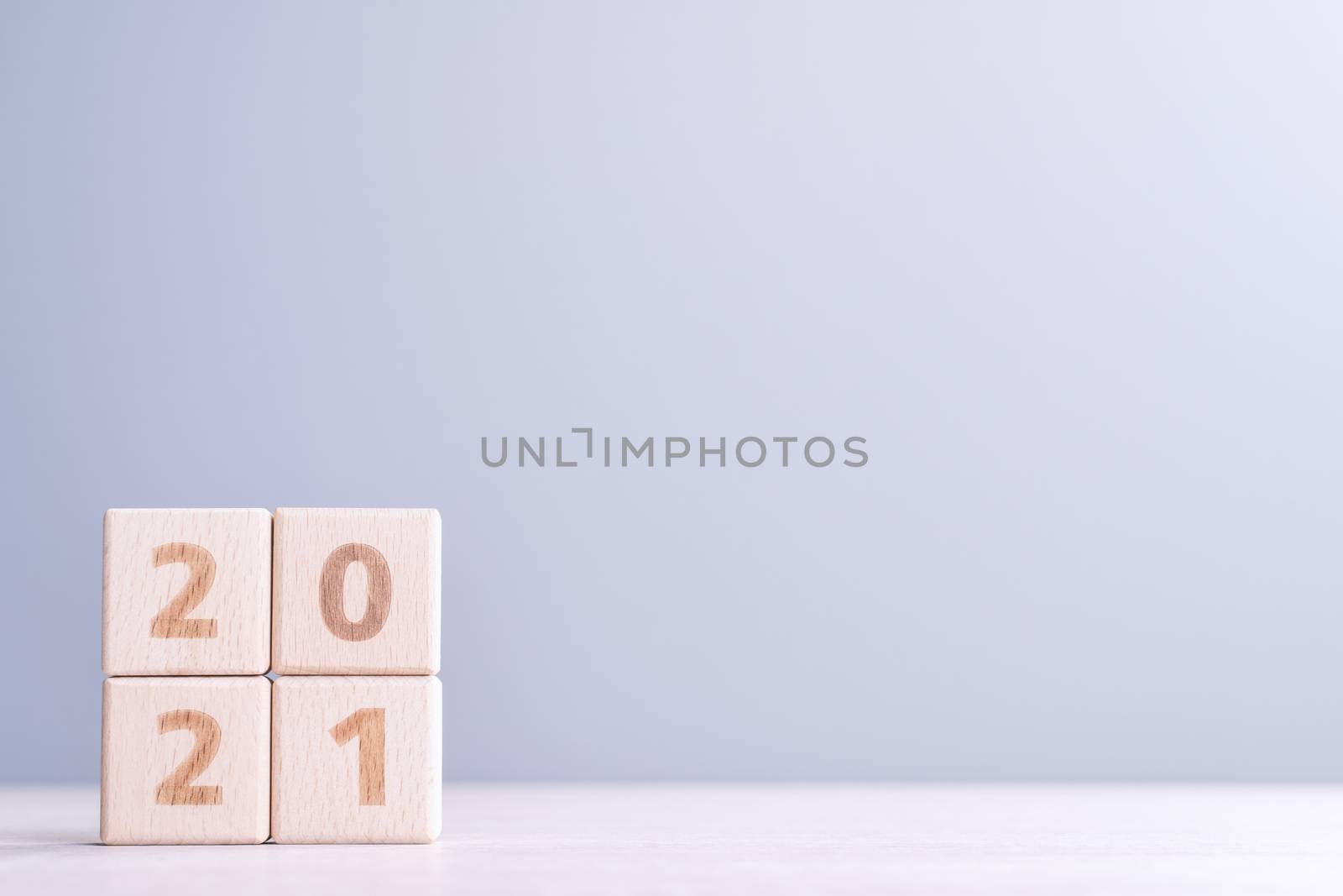 2021 New Year abstract design concept - Number wood block cubes isolated on wooden table and light mist blue background.