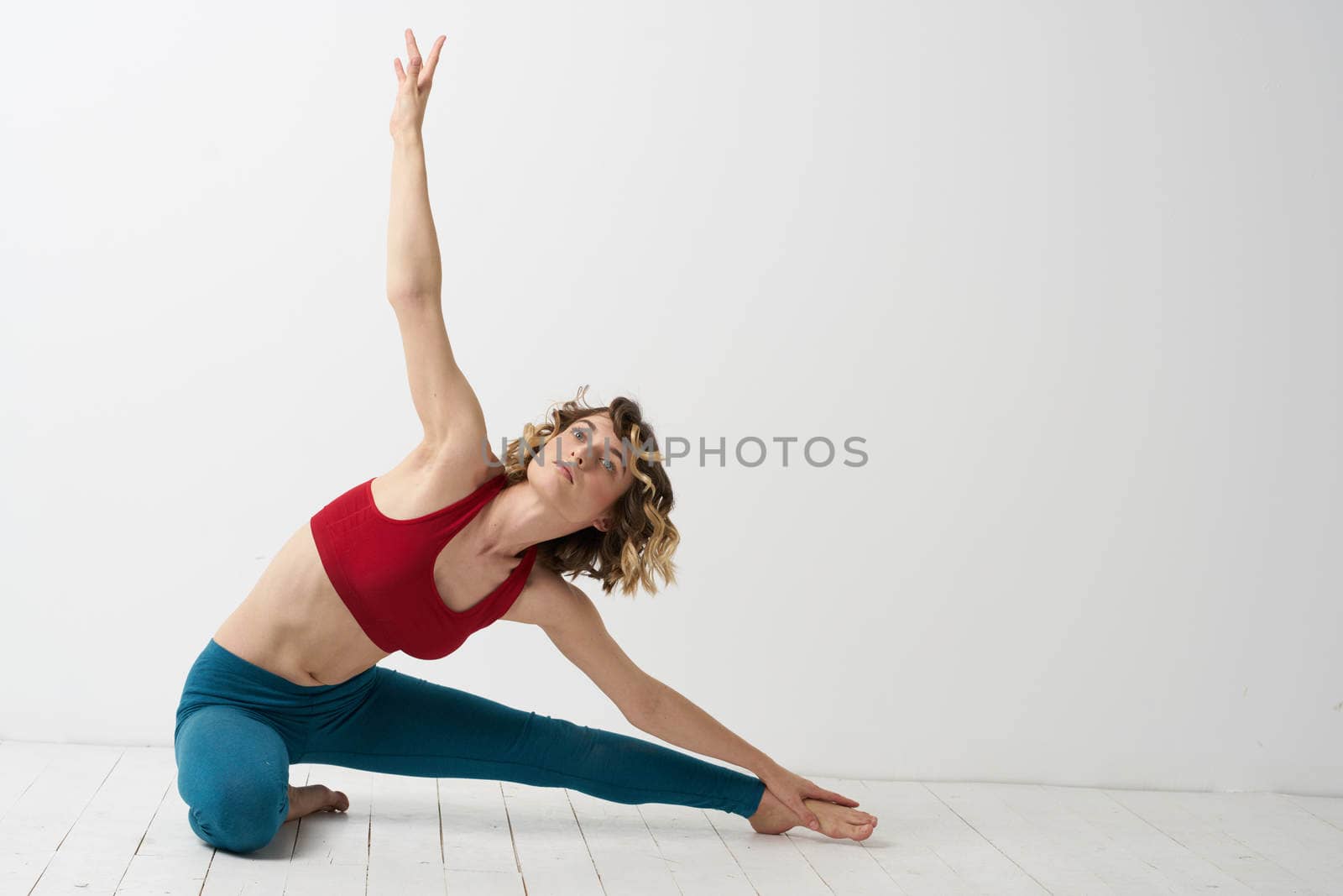 the girl is engaged in yoga on a light background Red T-shirt gesticulating with his hands. High quality photo