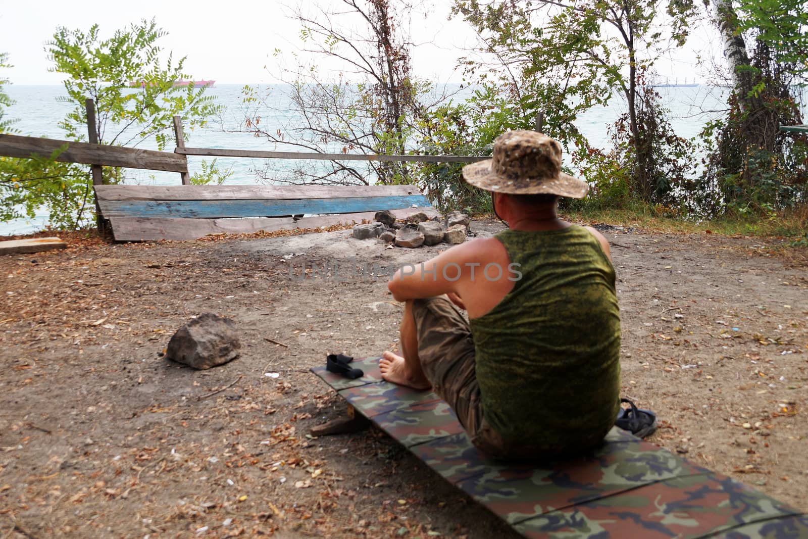 a one man sits and looks at the sea horizon from a height