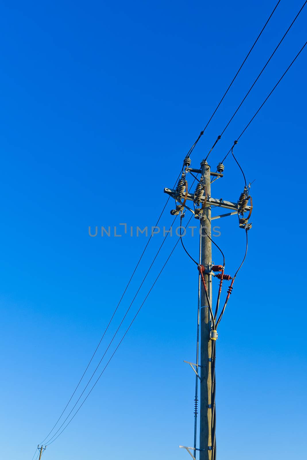 electric power sky lines and connections on a wooden post. wooden electricity post against blue sky. Electric power lines and wires with blue sky. by PhotoTime