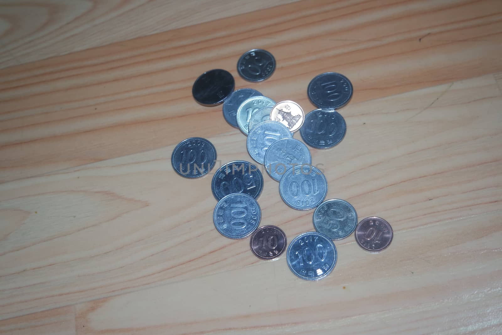 Silver shining Korean won coin scattered over a wooden floor.