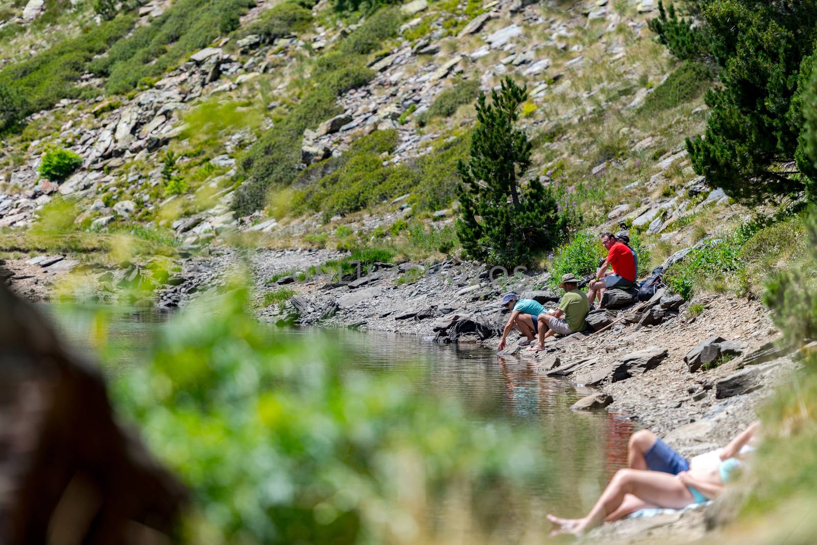 Group of tourists resting at Lago de les Truites in Andorra Pyre by martinscphoto