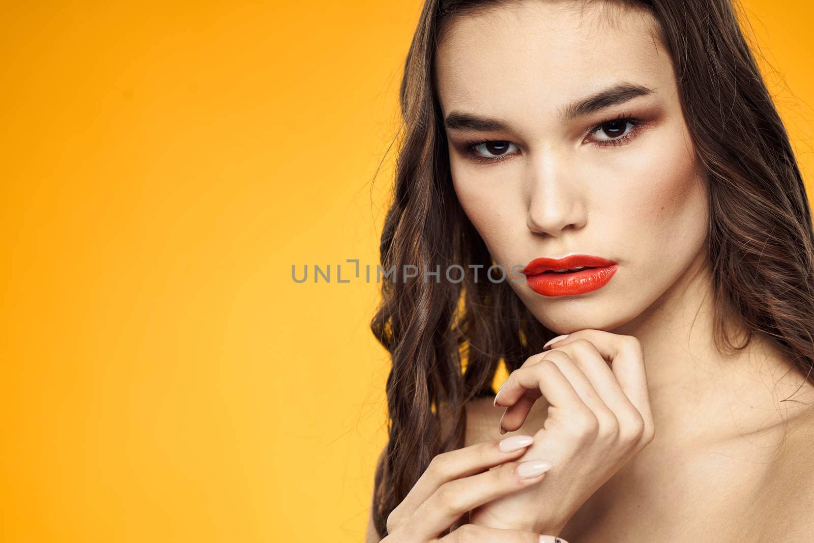 beautiful brunette red lips bare shoulders skin care yellow background. High quality photo