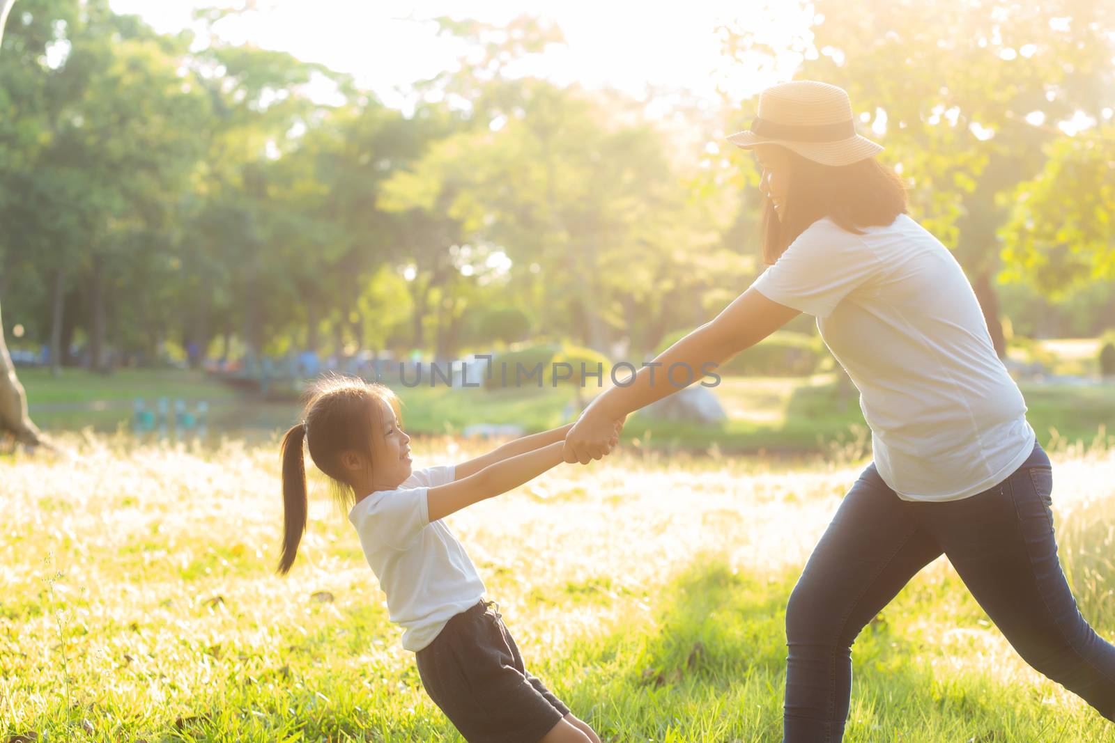 Young asian mother and little daughter playing the park with fun and happiness, family enjoy and relax and leisure together, mom and children smiling laughing in summer day.