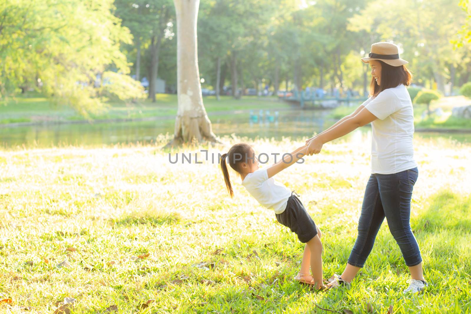 Young asian mother and little daughter playing the park with fun and happiness, family enjoy and relax and leisure together, mom and children smiling laughing in summer day.