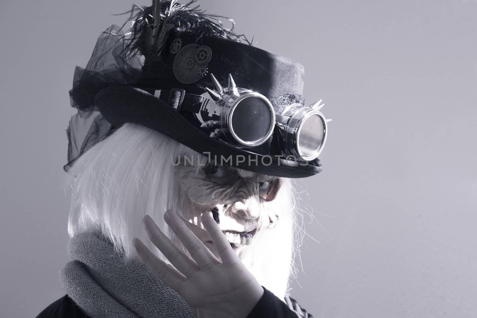 Woman with monster face and black hat wearing steampunk glasses. White hair.