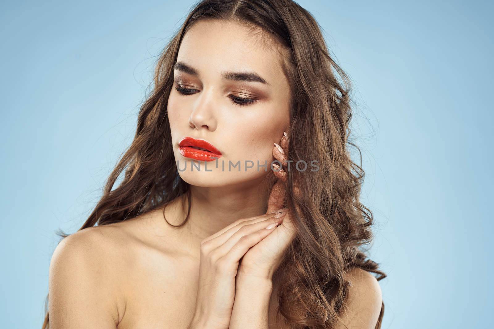 Elegant brunette fashionable hairstyle bright makeup naked shoulders close-up blue background. High quality photo