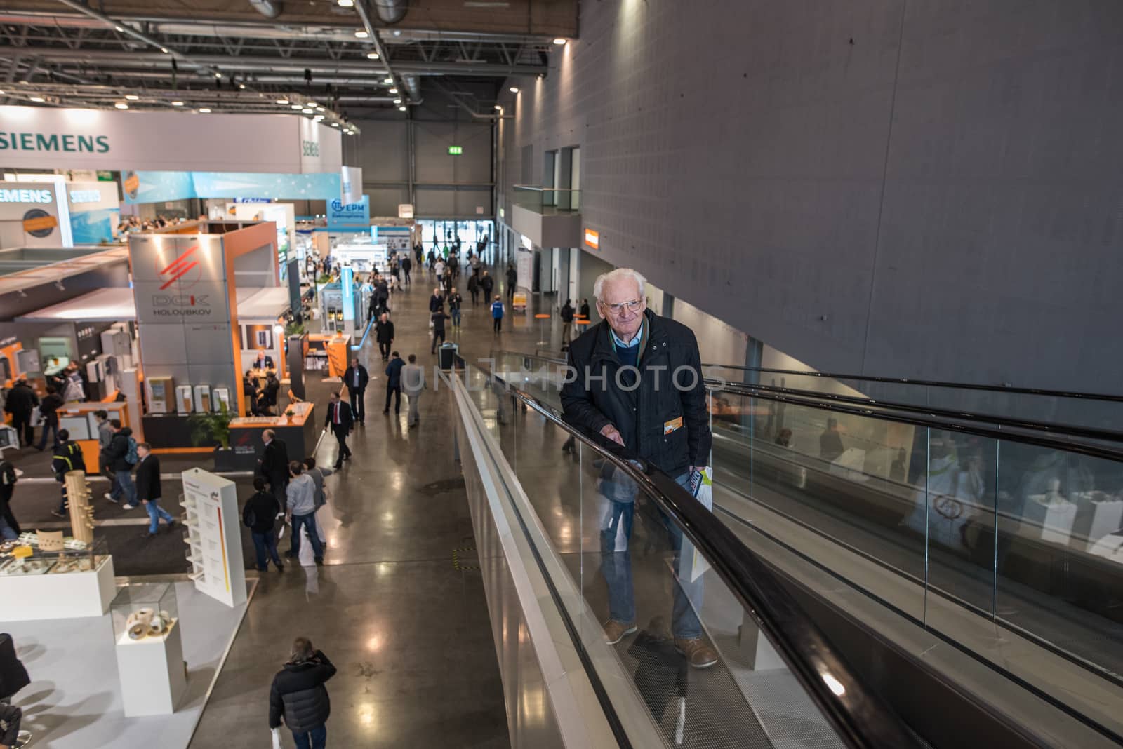 An old man is getting a lift by the mechanical stairs at the Amper convention at the Bno Exhibition Center. czech Republic