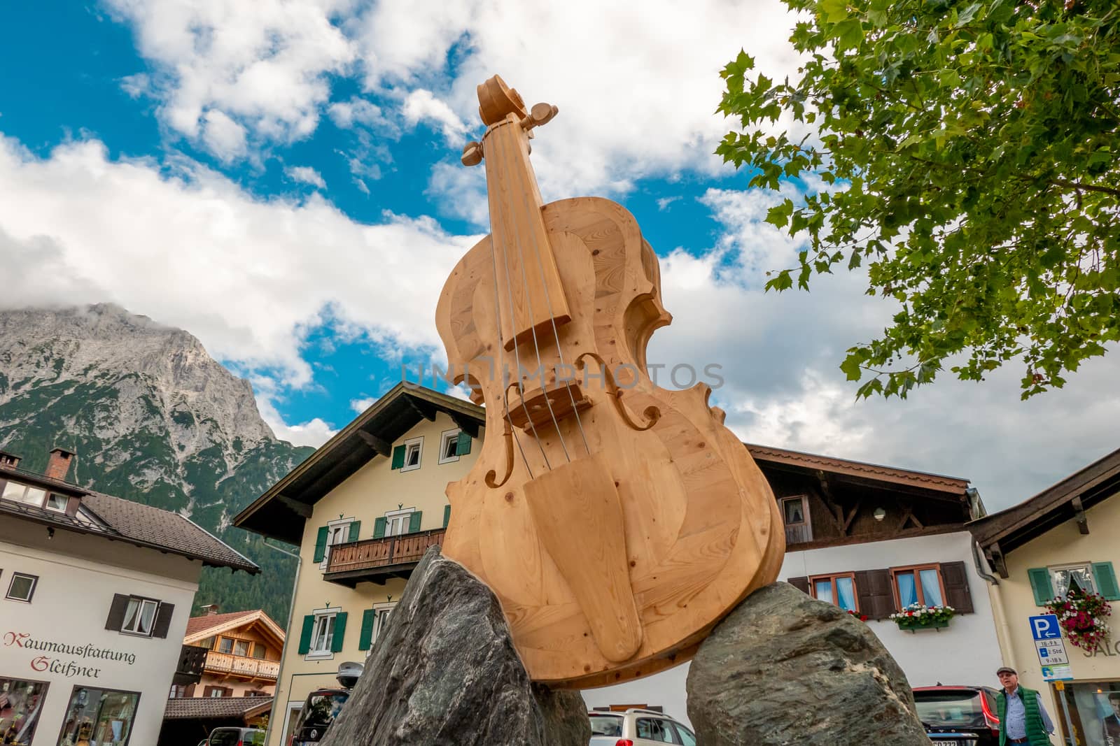 Mittenwald, Bavaria/Germany - 15.08.2020: A huge wooden violin with sides, body and fingerboard, built diagonally on two rocks and located in the middle of Mittenwald in Bavaria