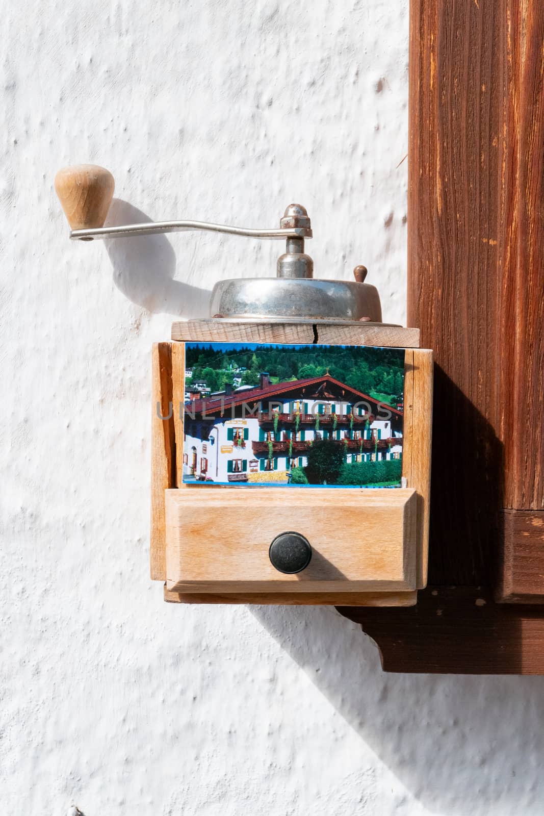 An old hand-operated coffee grinder on a wall of a hotel or pension, which is equipped with business cards to remove.