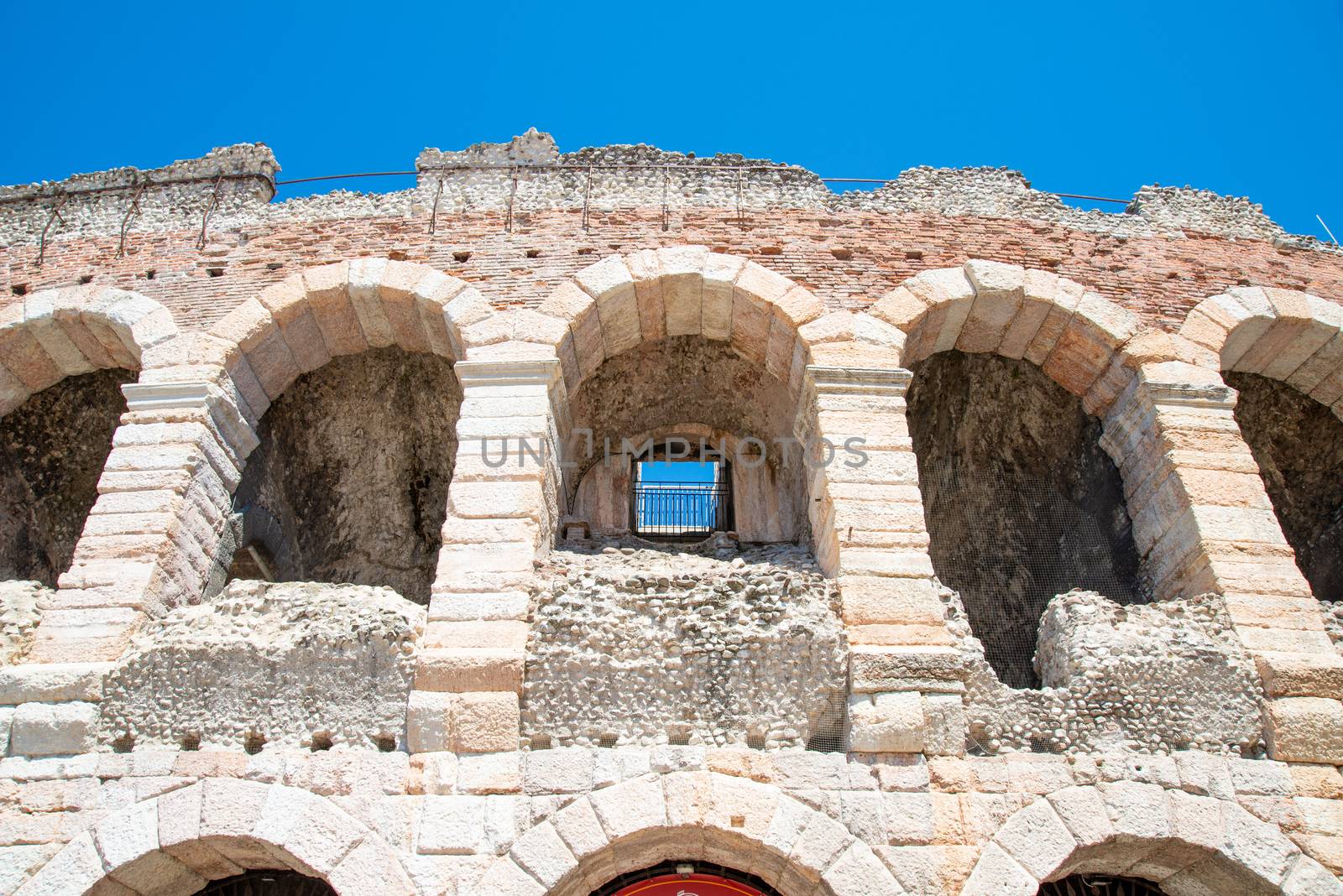 Several arches on the decayed external façade of the in amphitheater Verona with clear traces of decay and broken stones of marble and sandstone.