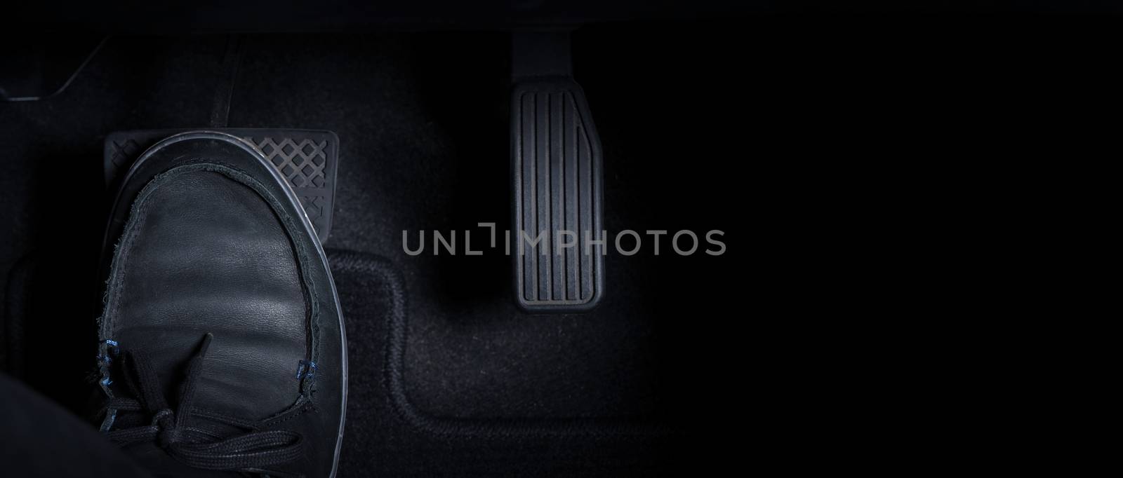 Close up images of man driving car by pushing accelerator and brake pedal with right foot black leather shoe and black jean pant. camera shot inside the japanese car.