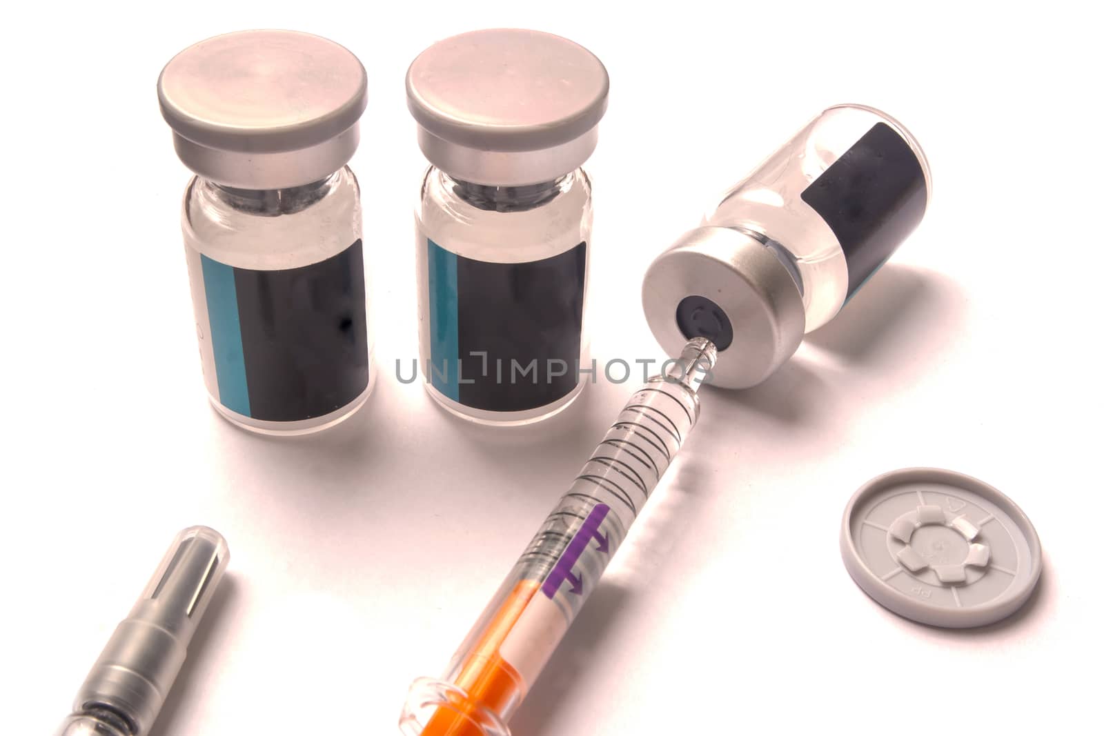 vaccine bottles, one of which is getting the vaccine in a syringe.