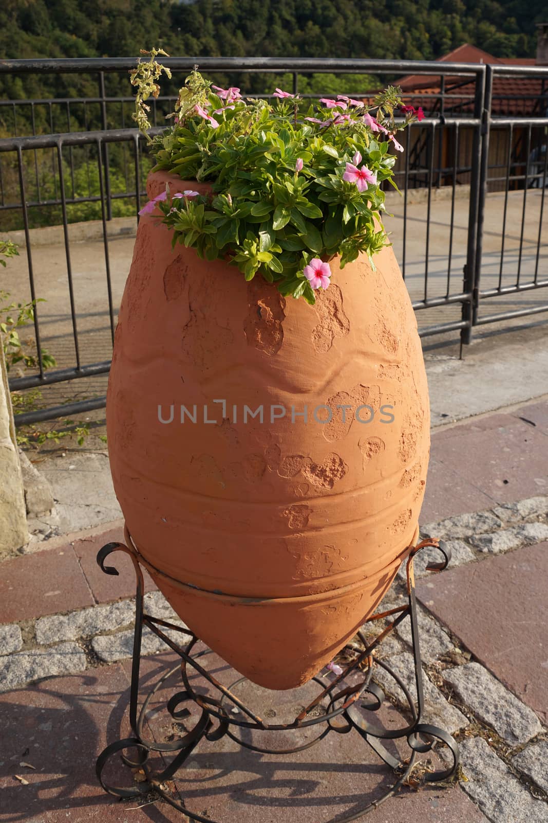 flowers in a large clay pot on a metal stand