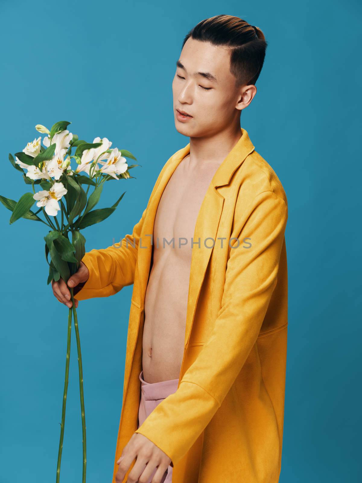 Man with a bouquet of white flowers on a blue background romance gifts nude torso jacket. High quality photo