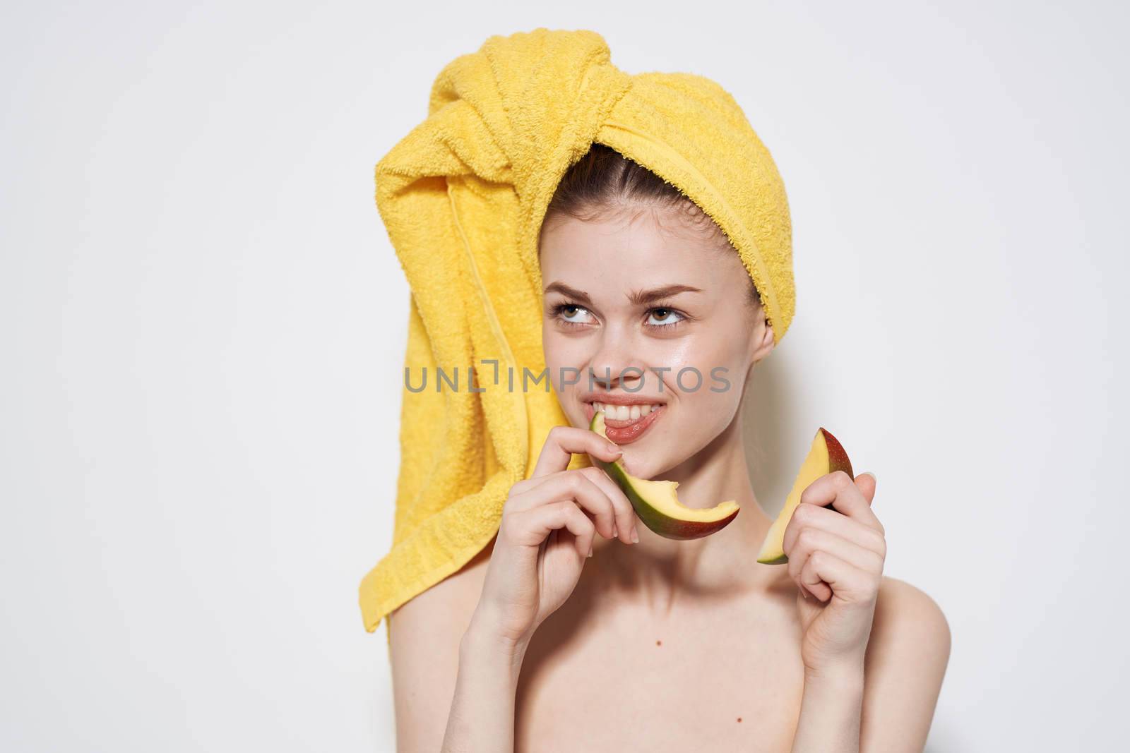 Cheerful woman in a yellow towel on her head eating manga health vitamins cropped view by SHOTPRIME