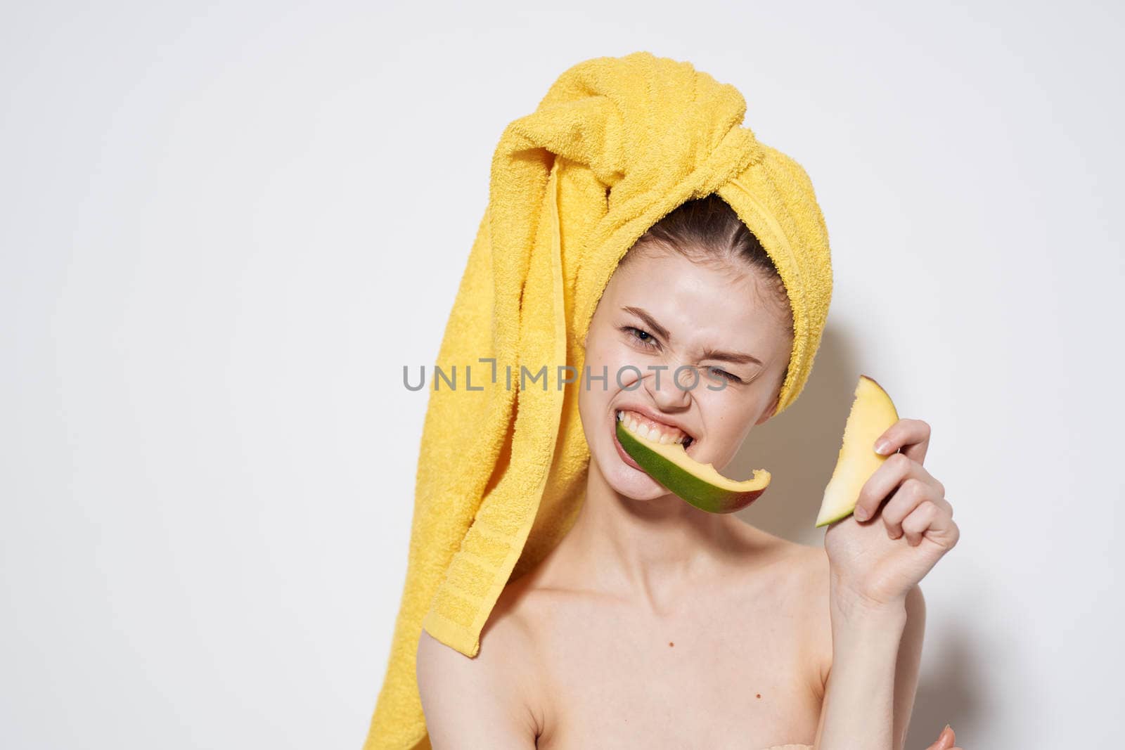 Woman with bare shoulders yellow towel on head mango exotic vitamins fruits. High quality photo