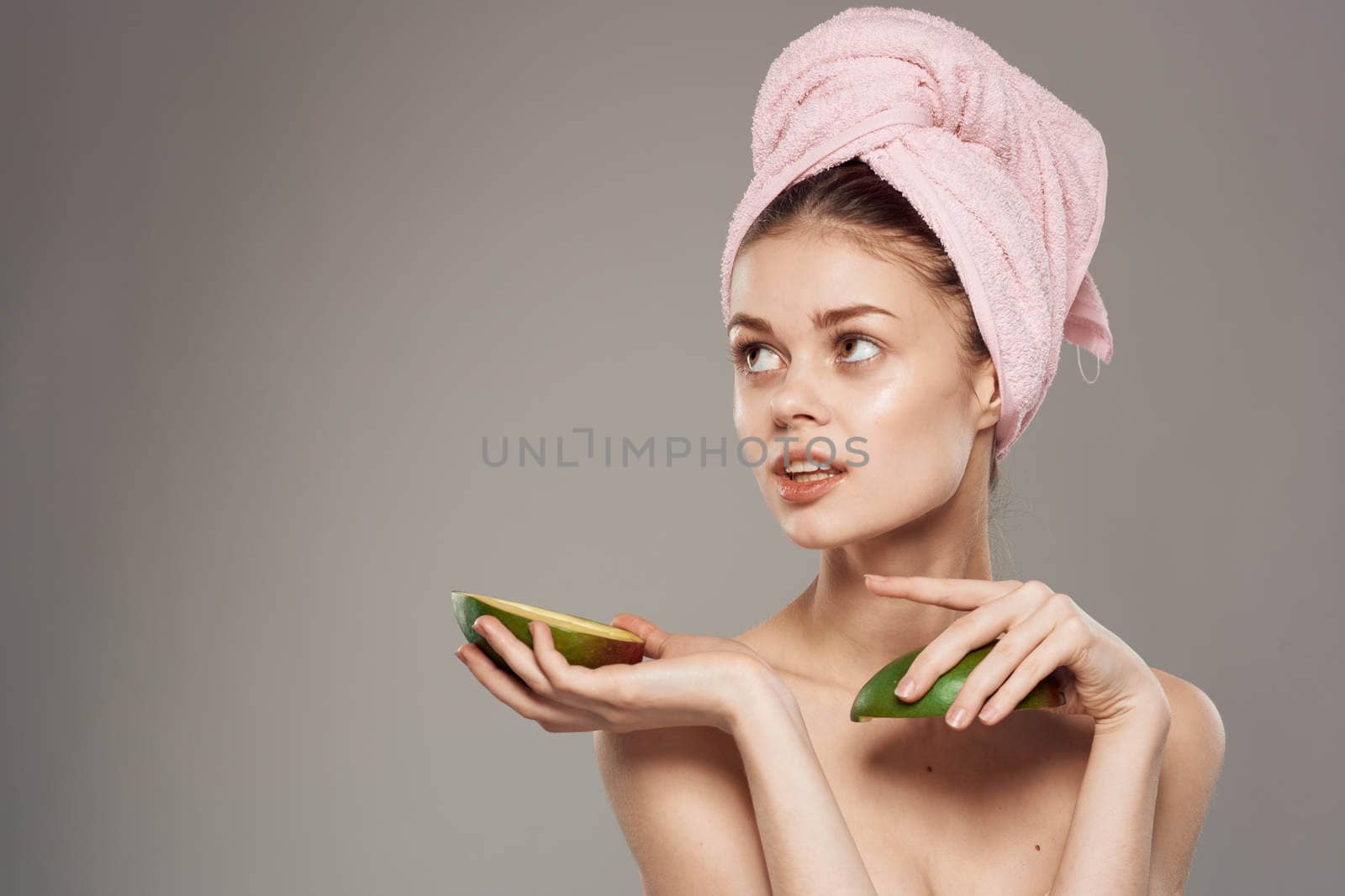 Woman holds a ripe mango in her hand bare shoulders with a towel on her head by SHOTPRIME