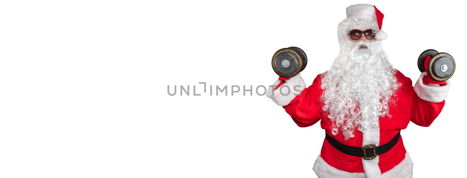 Santa Claus working out and pushing two dumbbells up in the air. Santa wearing sunglasses and a long white beard. Isolated on white background. Banner size, copy space.