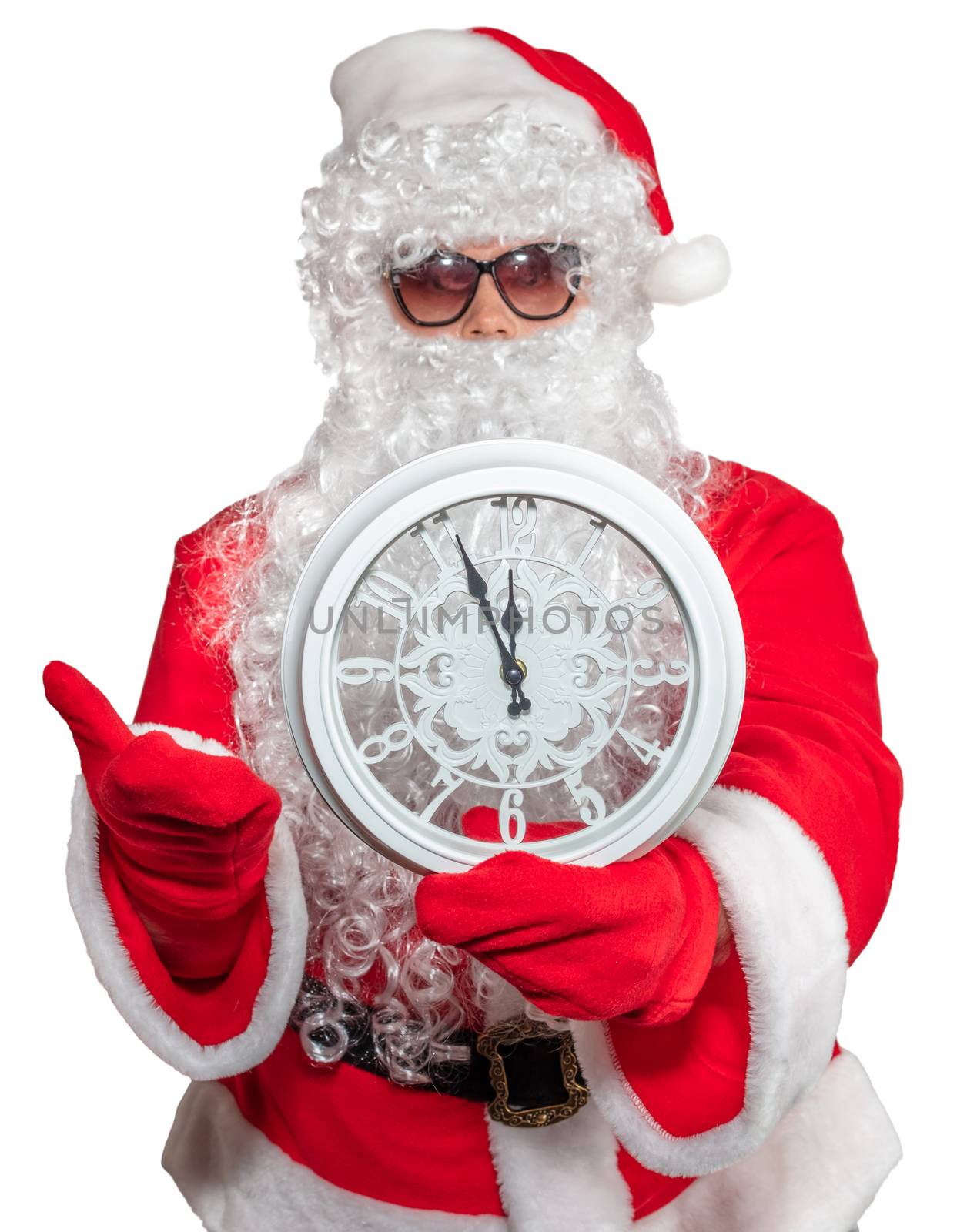 Santa Claus holding a white clock which shows five minutes to midnight. New year's eve concept. He is wearing sunglasses, long white beard. Isolated on white background.