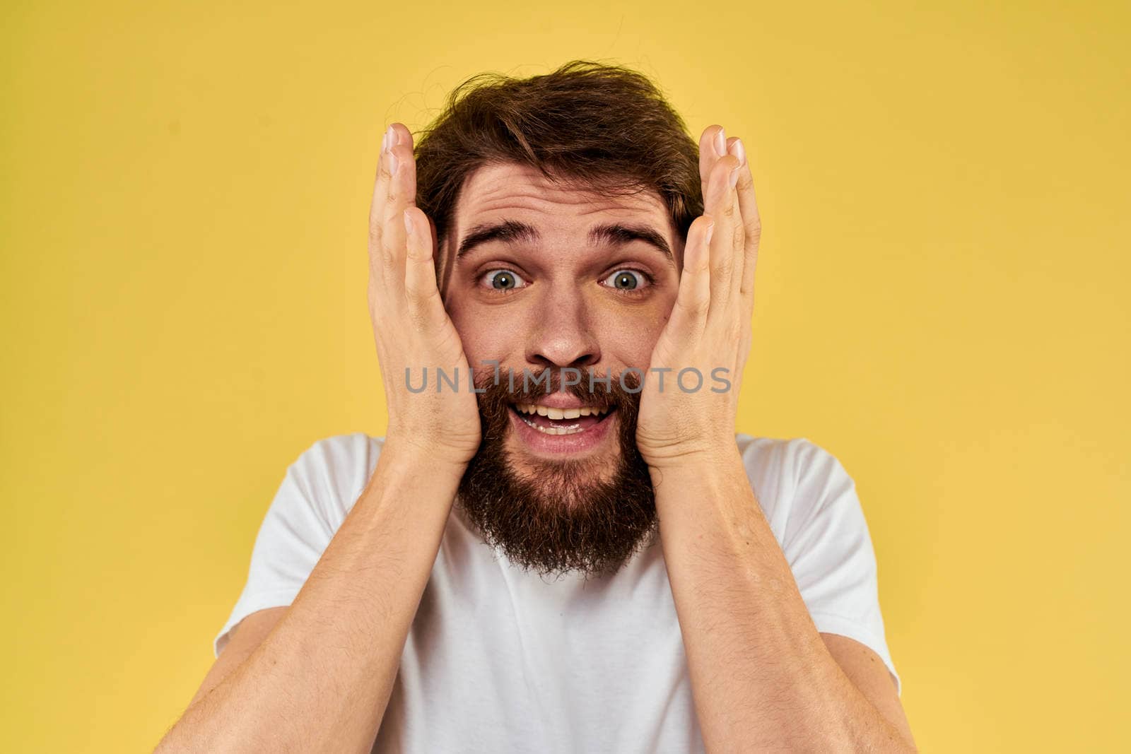 A man in a white t-shirt gestures with his hands lifestyle cropped view yellow background more fun. High quality photo